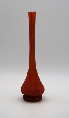 un vase rouge posé sur une surface blanche