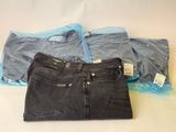 three pairs of jeans are sitting on a table next to a plastic bag