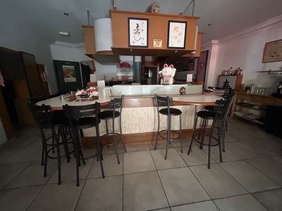 des tables et des tabourets dans une cuisine équipée d'un plan de travail et d'une télévision