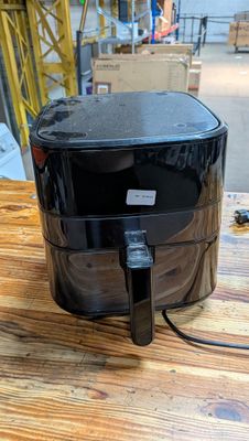une friteuse à air chaud noire posée sur une table en bois