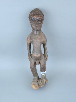 une vieille statue en bois d'un homme avec un chapeau sur la tête