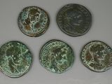 four ancient roman coins are shown in a row on a white surface