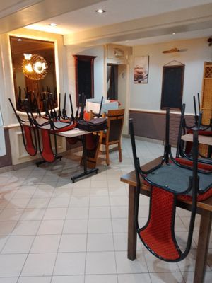Il y a beaucoup de chaises et de tables dans cette pièce aux carreaux blancs.