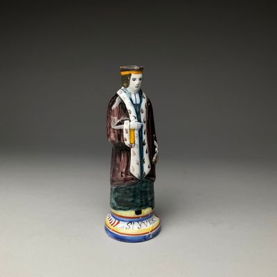 une image représentant une figurine d'un homme portant un chapeau et une robe