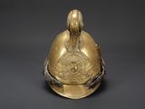 a gold helmet with a bird on top of it on a black background