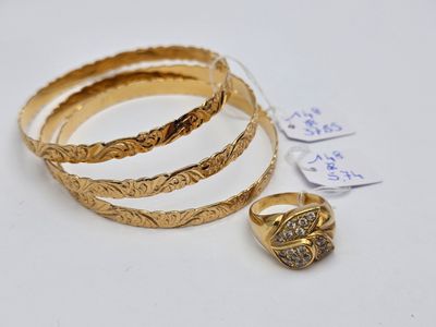 three gold rings and a ring on a white surface