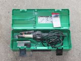 une boîte verte contenant des outils, posée par terre