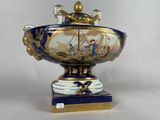 a blue and white vase with a gold decoration on it