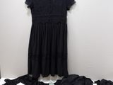 une robe en dentelle noire suspendue à un cintre, à côté d'une pile de vêtements