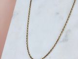 un collier à chaîne en or posé sur une surface en marbre