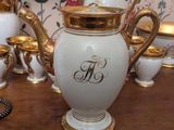 a white and gold vase with a monogram on it
