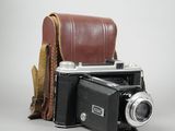 a brown leather case holding a camera and a brown leather case