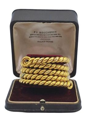 un gros plan sur une paire de bracelets en or tressé dans un écrin