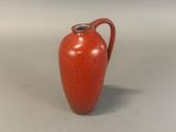 a red vase with a handle on a table