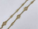 two long gold chain bracelets on a white surface
