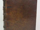 an old book with a brown leather cover sitting on a white surface