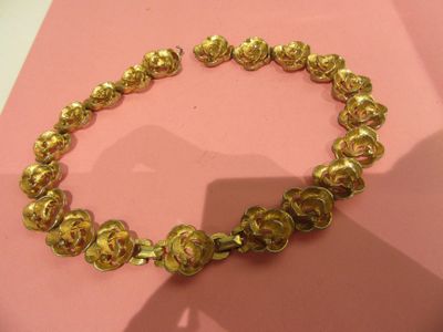 gold plated bracelet on pink background with shadow of a person