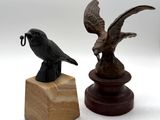 a statue of a bird on a pedestal next to a statue of a bird on a stand