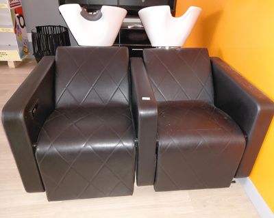 deux fauteuils en cuir marron sur lesquels sont posés des vases blancs