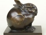 sculpture en bronze représentant un lapin, posée sur un socle en marbre, sur fond blanc