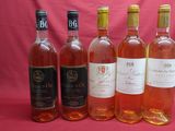 six bottles of wine are lined up in a row on a pink background