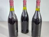 three bottles of red wine sit on a table next to each other