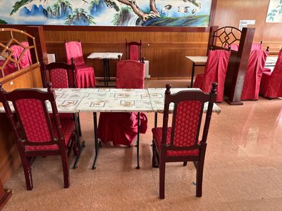 des tables et des chaises recouvertes de nappes rouges dans un restaurant où est accroché un grand tableau au mur