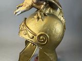 brass figurine of an eagle perched on top of a helmet