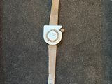 watch on a black surface with a brown strap and a white face