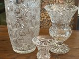 three glass vases sitting on a table next to a chair