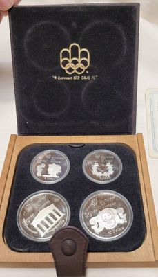 four silver coins in a box with the olympic logo on them