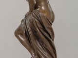 bronze statue of a woman kneeling on a rock with her hands on her knees