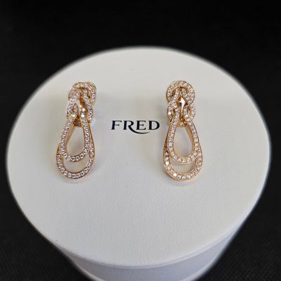 Deux paires de boucles d'oreilles sont posées sur un présentoir blanc.