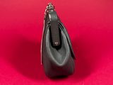 the small black purse is sitting on a red surface