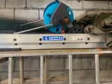un ventilateur bleu posé sur une étagère, à côté d'un mur de briques