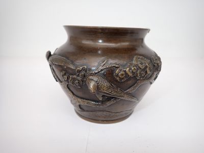 un vase marron orné d'oiseaux, posé sur une table