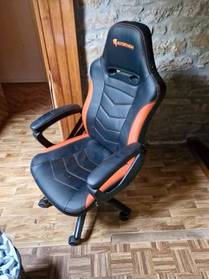 une chaise de bureau noire et orange posée sur un parquet en bois massif