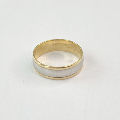 gros plan d'une bague en or et en argent sur une surface blanche