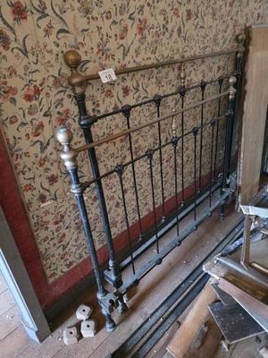 a bed with a metal frame in a room with a wallpapered wall