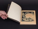 quelqu'un tient un livre ouvert sur lequel figure l'image d'un oiseau