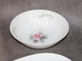 two white bowls with pink flowers on them on a table