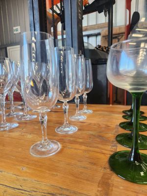 many wine glasses lined up on a wooden table