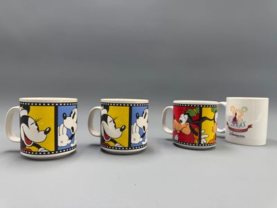 Trois tasses à café Disney sont alignées sur une table