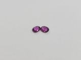 a pair of purple sapphires sitting on top of a white surface