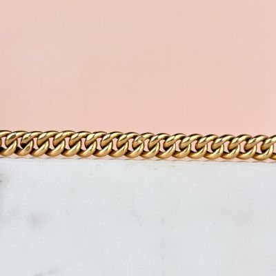 un gros plan d'un bracelet à chaîne en or posé sur une surface en marbre