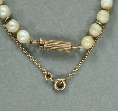 un gros plan sur un collier orné de perles et muni d'un fermoir en or