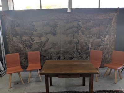 trois chaises et une table devant une tapisserie