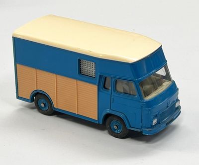 un petit camion jouet bleu et beige posé sur une surface blanche