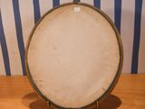 a drum on a wooden table with a striped wall in the background