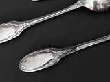 three silver spoons on a black surface with a black background